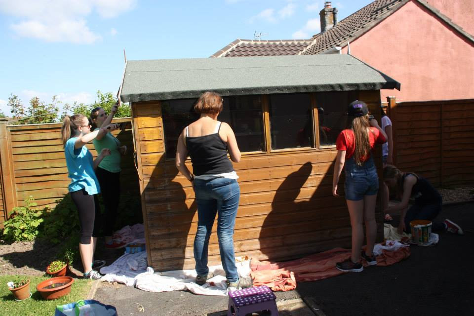 Photo: Love Congresbury / SWNS.com. Residents of Congresbury varnish a shed - one of 800 random acts of kindness performed by the people in the village.